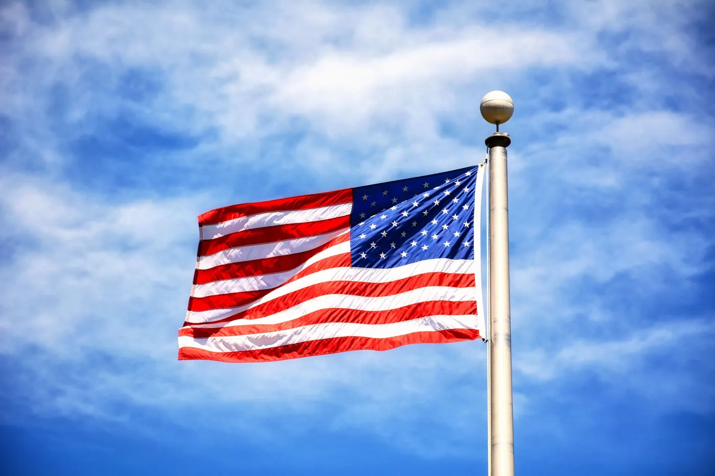 The American flag flying against a blue sky, Sopariwala supplies tobacco leaf across the states