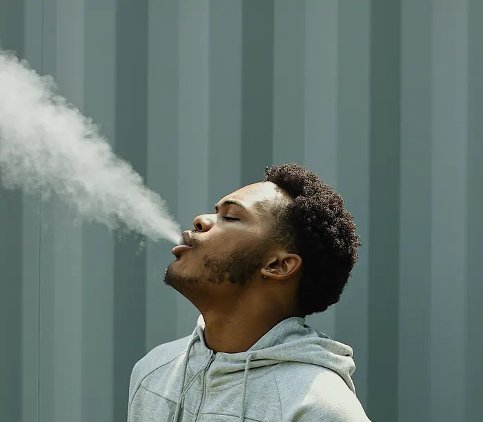 Young American exhaling a thick cloud of hookah smoke, the consumer pipe and cigar and hookah companies serve